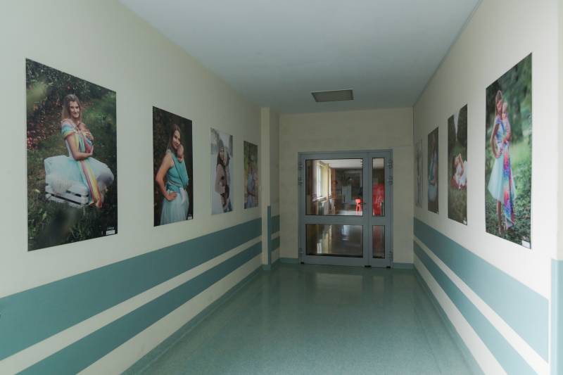 korytarz, na ścianach duże fotografie mam ze swoimi dziećmi w tle drzwi i dalsza część korytarza